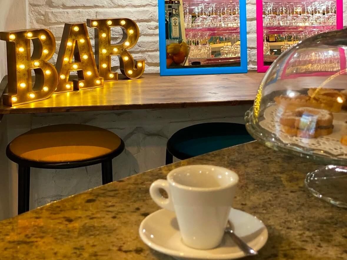 Interno del bar con lettere luminose, sgabelli e bancone in marmo